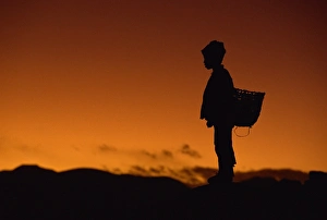 Young boy silhouetted against sky at dusk, Tibet, China, Asia Young boy silhouetted against sky at dusk, Tibet, China, Asia