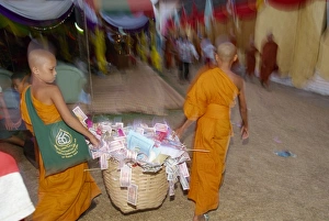 Two young monks carrying basket of donations during Two young monks carrying basket of donations during