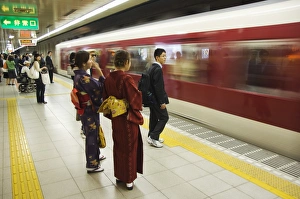 Young women wearing kimono waiting for train to arrive Young women wearing kimono waiting for train to arrive