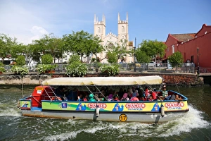 Church of St. Francis Xavier and a tourist sightseeing boat on the Sungai Melaka river in Church of St. Francis Xavier and a tourist sightseeing boat on the Sungai Melaka river in
