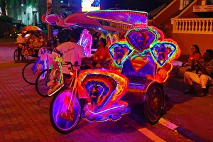 Illuminated decorated kitsch cycle trishaw rickshaw with soft toys at night in Malacca Illuminated decorated kitsch cycle trishaw rickshaw with soft toys at night in Malacca