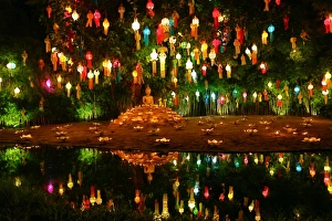Lanterns and candles reflected in a pool with a Buddha stature for the Loy Krathong Lanterns and candles reflected in a pool with a Buddha stature for the Loy Krathong