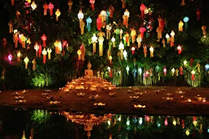 Lanterns and candles reflected in a pool with a Buddha stature for the Loy Krathong Lanterns and candles reflected in a pool with a Buddha stature for the Loy Krathong