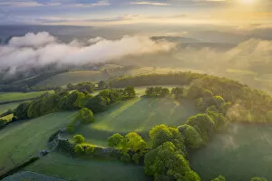 Aerial vista of Cadbury Castle Iron Age Hillfort in early morning sunlight, Devon