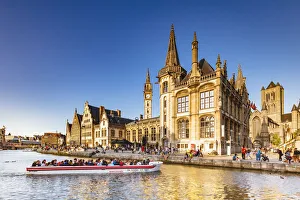 A boat with tourists on the canal with the Ghent town buildings reflecting at sunset A boat with tourists on the canal with the Ghent town buildings reflecting at sunset
