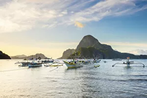 Images Dated 25th December 2014: Boats anchored in Bacuit Bay and Cadlao Island at sunset seen from Caalan Beach, El Nido