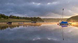 Boats on a reflective Wimbleball Reservoir at sunrise, Exmoor National Park, Somerset Boats on a reflective Wimbleball Reservoir at sunrise, Exmoor National Park, Somerset