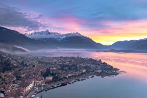 Burning sky at dawn over the snowcapped mountains and Domaso old town, aerial view Burning sky at dawn over the snowcapped mountains and Domaso old town, aerial view