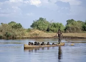 A Dassanech man ferries people in a large dug-out canoe