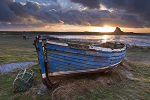 Decaying fishing boat on Holy Island at dawn, with Lindisfarne Castle beyond, Northumberland Decaying fishing boat on Holy Island at dawn, with Lindisfarne Castle beyond, Northumberland