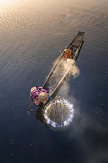Elevated view of fisherman catching fish from boat using traditional conical net at Elevated view of fisherman catching fish from boat using traditional conical net at
