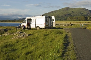 A family on a camping holiday sit outside their campervan A family on a camping holiday sit outside their campervan