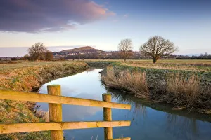 First light of morning on Glastonbury Tor viewed from the River Brue on the Somerset First light of morning on Glastonbury Tor viewed from the River Brue on the Somerset