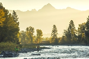 Fly fisherwoman & fisherman casting & fishing on river, British Columbia, Canada Fly fisherwoman & fisherman casting & fishing on river, British Columbia, Canada