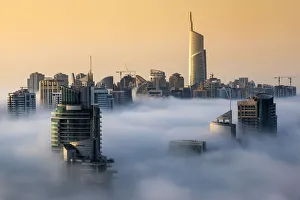 Foggy sunrise with Dubai Marinas skyscrapers towering over the low clouds Foggy sunrise with Dubai Marinas skyscrapers towering over the low clouds
