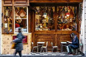 Girl reading in front of a traditional Salumeria in Bologna, Emilia Romagna, Italy Girl reading in front of a traditional Salumeria in Bologna, Emilia Romagna, Italy