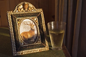 A glass of whisky rests beside a shell encrusted picture A glass of whisky rests beside a shell encrusted picture