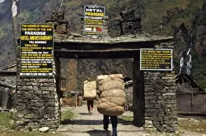 Annapurna Gallery: Heavily laden porters enter village gateway