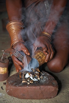 A Himba woman lights a small fire made of woodshavings A Himba woman lights a small fire made of woodshavings