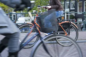 Holland, Amsterdam, riding a bicycle over a canal bridge Holland, Amsterdam, riding a bicycle over a canal bridge