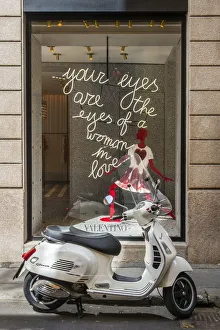 Italian Vespa scooter parked in Via Montenapoleone fashion street with Valentino shop Italian Vespa scooter parked in Via Montenapoleone fashion street with Valentino shop