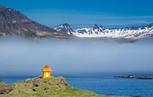Lighthouse on cliff at Djupivogur against mountain range, East Iceland, Iceland Lighthouse on cliff at Djupivogur against mountain range, East Iceland, Iceland