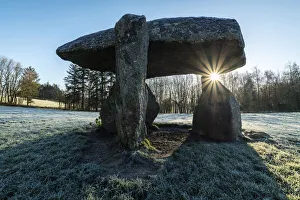 Low winter sun rising through the Neolithic dolmen Spinster's Rock near Drewsteignton in Low winter sun rising through the Neolithic dolmen Spinster's Rock near Drewsteignton in