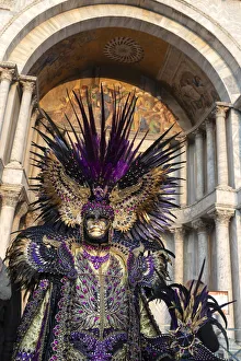 A man in an elaborate costume stands in front of the Basilica Saan Marco in St A man in an elaborate costume stands in front of the Basilica Saan Marco in St