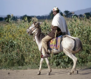 Debre Birhan Gallery: A man rides to market on his gaily-caprisoned pony