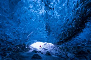 Man standing at entrance to an ice cave beneath a glacier, Iceland, Europe Man standing at entrance to an ice cave beneath a glacier, Iceland, Europe