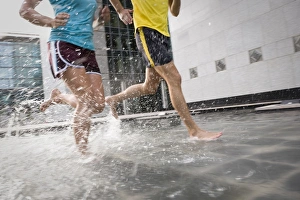 A man and woman running barefoot through water A man and woman running barefoot through water