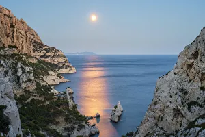 Full moon rising over ocean and Mediterranean landscape and Calanque de Sugiton at dusk Full moon rising over ocean and Mediterranean landscape and Calanque de Sugiton at dusk