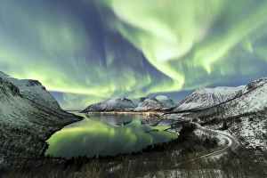 Northern lights and stars light up the snowy peaks reflected in the cold sea Bergsbotn Northern lights and stars light up the snowy peaks reflected in the cold sea Bergsbotn
