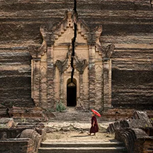 Pagodas Collection: Novice monk walking towards unfinished Pahtodawgyi pagoda known for a crack caused by a