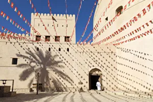 An Omani man walks into Bahla Fort decorated to celebrate the birthday of Sultan Qaboos An Omani man walks into Bahla Fort decorated to celebrate the birthday of Sultan Qaboos