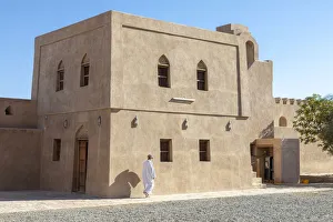 An Omani man walks in front of a restored building in Bahla Fort, Tanuf, Oman An Omani man walks in front of a restored building in Bahla Fort, Tanuf, Oman