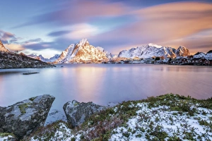 The pink sky at sunrise illuminates Reine village with its cold sea and the snowy peaks The pink sky at sunrise illuminates Reine village with its cold sea and the snowy peaks
