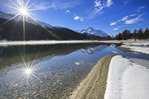 Rays of winter sun illuminate Lake Silvaplana still partially frozen Maloja Engadine Rays of winter sun illuminate Lake Silvaplana still partially frozen Maloja Engadine