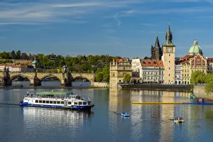 River cruise boat on Vltava River with Smetana Museum and Charles Bridge in the background River cruise boat on Vltava River with Smetana Museum and Charles Bridge in the background
