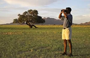 Images Dated 7th February 2006: A safari guide scans the horizon with his binoculars