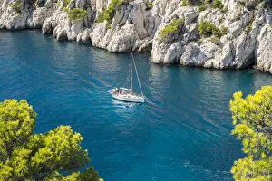 Sailboat passing through emerald blue water of Calanque de Port-Pin, Cassis Sailboat passing through emerald blue water of Calanque de Port-Pin, Cassis