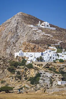 shepherd with goats and the Hora Village in Folegandros, Cyclades Islands, Greece shepherd with goats and the Hora Village in Folegandros, Cyclades Islands, Greece