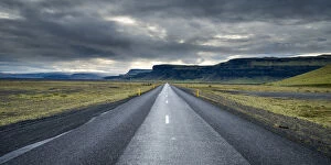 Sudurland Region Gallery: Straight empty road leading towards mountains against cloudy sky, South Iceland, Iceland