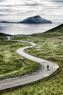 Stremnoy island, Faroe Islands, Denmark. Man standing on a bending road. (MR) Stremnoy island, Faroe Islands, Denmark. Man standing on a bending road. (MR)