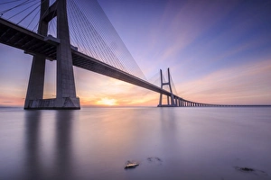 The sun rises on the Vasco da Gama Bridge that spans the Tagus River in Parque das The sun rises on the Vasco da Gama Bridge that spans the Tagus River in Parque das