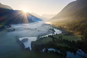 Sunburst during a foggy sunrise over Stryneelva river and fields, aerial view, Stryn Sunburst during a foggy sunrise over Stryneelva river and fields, aerial view, Stryn