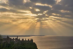 Sunrays over Dunluce Castle at Sunset, County Antrim, Northern Ireland Sunrays over Dunluce Castle at Sunset, County Antrim, Northern Ireland