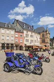Three-wheeled motorbikes with the historic court house Denzelt at Echternach, Luxembourg Three-wheeled motorbikes with the historic court house Denzelt at Echternach, Luxembourg