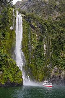 Tourist boat approaching Stirling Falls in Milford Sound in Fiordland National Park Tourist boat approaching Stirling Falls in Milford Sound in Fiordland National Park