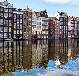 Traditional buildings along the Damrak reflected in the canal, Amsterdam, the Netherlands Traditional buildings along the Damrak reflected in the canal, Amsterdam, the Netherlands